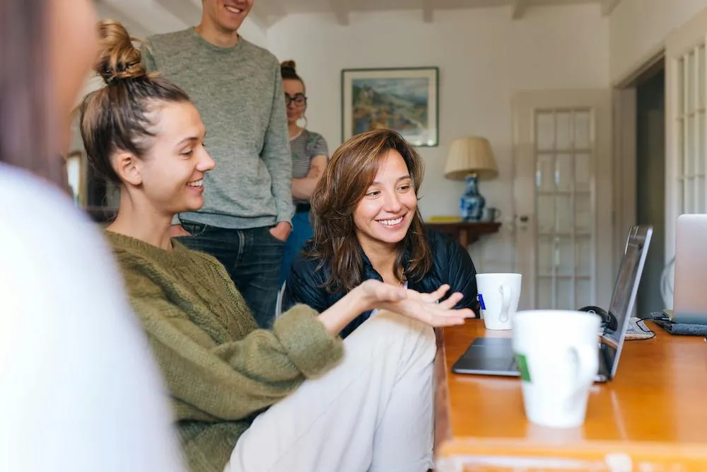 happy group group of young people in living room at laptop